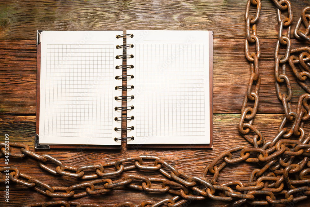 Wall mural open blank page notebook with copy space and old rusty iron chain on the wooden table background. to