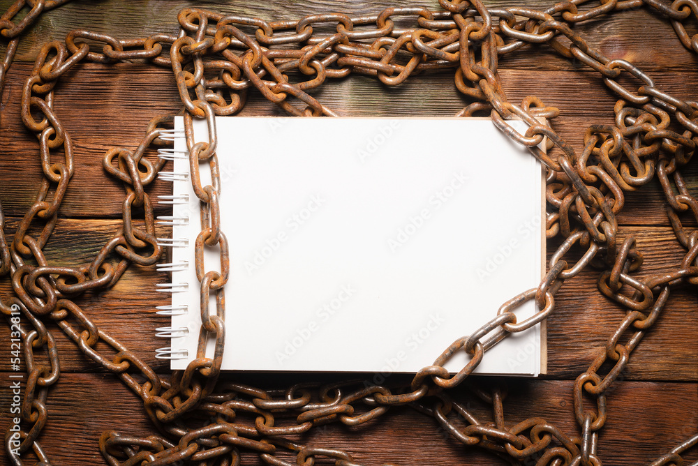 Wall mural open blank page notebook with copy space and old rusty iron chain on the wooden table background. to