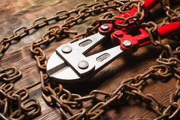 Bolt cutters rebar shears and iron chain on brown wooden workbench background close up. Top view.