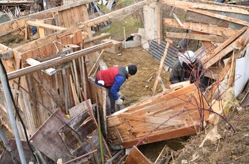 Workers disassemble and demolish an old wooden hut by hand
