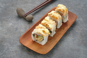Sushi Rolls Mayo with crab stick, ebi, cucumber served on wooden plate

