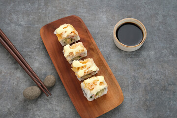 Sushi Rolls Mayo with crab stick, ebi, cucumber served on wooden plate
