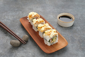 Sushi Rolls Mayo with crab stick, ebi, cucumber served on wooden plate
