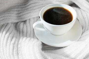 Details of a still life in the living room of a home interior. A white cup of coffee and a scarf by the frozen window. Cozy autumn winter concept.