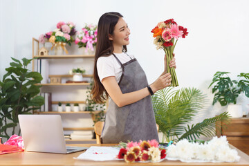 Florist concept, Female florist holds colorful gerbera to prepare for making flower bouquet in shop
