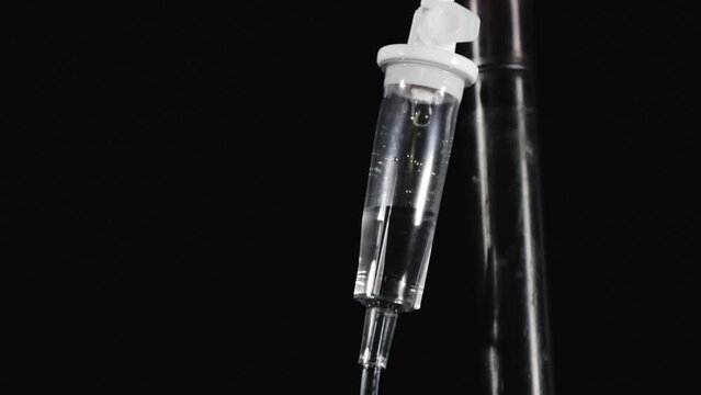 Closeup footage of a static IV drip chamber on a black background