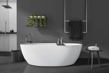 Front view on dark bathroom interior with bathtub, stool, towels