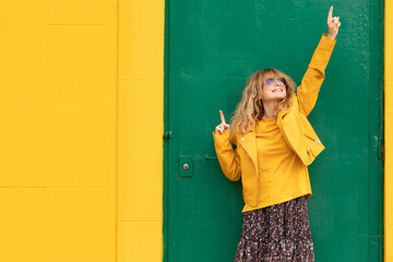 happy middle aged woman at green door with yellow wall