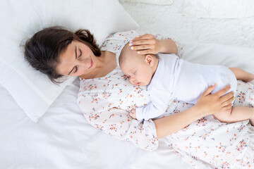 mom and newborn baby sleep together, mom puts baby to sleep on the bed in the bedroom, the concept...