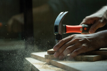 A carpenter furniture maker hammers a nail into the back of the cabinet with a hammer