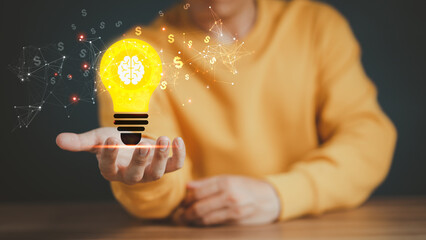 Man holding a glowing abstract light bulb on a wooden table, business problem solving ideas and creative marketing ideas Inventing and learning new things.