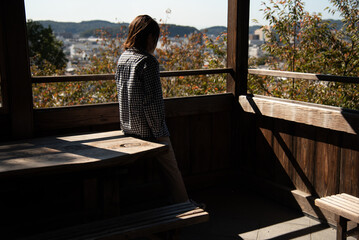 窓辺の机に腰掛ける女性