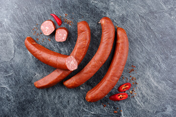 Traditional raw Bavarian spicy bratwurst with chilli offered as a top view on rustic grey board with text space - obrazy, fototapety, plakaty