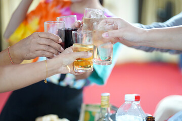 Hands clinking drinking glasses with friends at a fun and happy party.,select focus