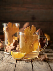 Ginger tea with lemon in a glass cup on an old wooden board.