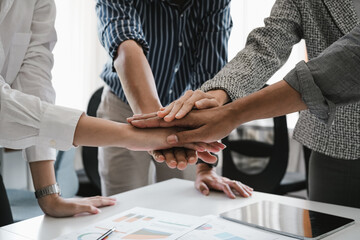 Close up happy diverse business people putting hands together, showing support and unity. Multiracial colleagues involved in team building activity. Staff training concept, start working together.