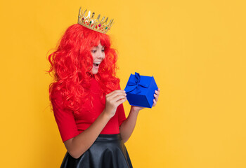 shocked child in crown with present box on yellow background