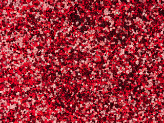 Red glitter texture closeup. Saturated shiny holographic background for Christmas desktop, holiday New Year, xmas seasonal decoration, valentin day, party greeting and wedding invitation card element.