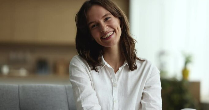 Close up portrait petty housewife relax on comfort sofa smile staring at camera look happy, spend carefree weekend leisure alone at own or rented home feel satisfied. Tenancy, well-being life concept