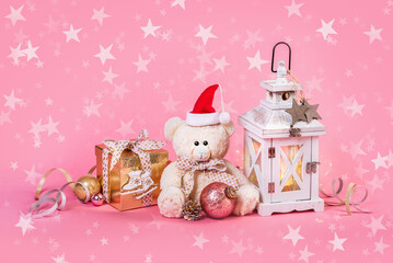 Merry Christmas and Happy New Year greetings for children. Teddy bear, a gift in a box and Christmas decorations on a pink background
