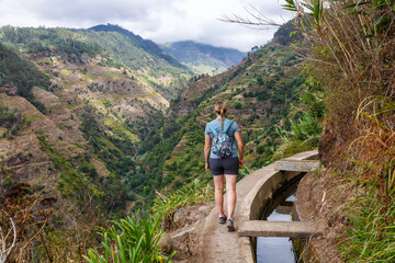 Fototapeta na wymiar Young woman on hiking trail along Levada Nova hike tour on Madeira island in Portugal
