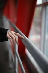 Obraz premium the girl's hand slides along the handrail against the background of red and metallic lines