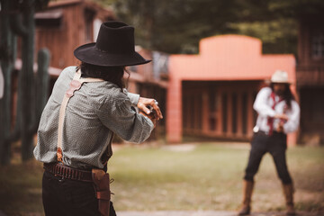 Backside view of cowboy while standing gun prepares on gunfight in cowboys village is cowboy...