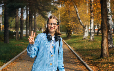 A young teenage girl wearing headphones is outside on a sunny day. The concept of joy and relaxation.