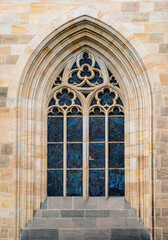 Fototapeta na wymiar Gothic arched window with stained glass at The St. Vitus Cathedral in Prague Castle, outside view. Stone decor elements of Christian Catholic temple in medieval style in Praga, Czech Republic.