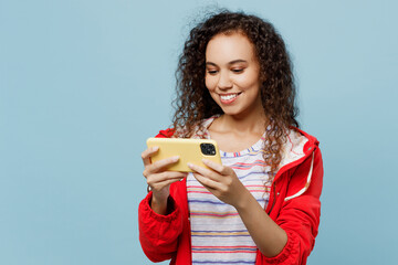 Young woman of African American ethnicity wear red jacket using play app on mobile cell phone...