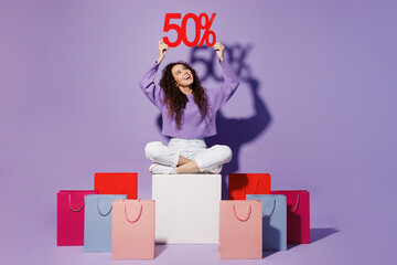 Full size young woman wear pullover sit near shopping paper package bag hold overhead up 50 %...