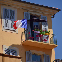 A balcony with plants, an umbrella, chairs, table and a France flag