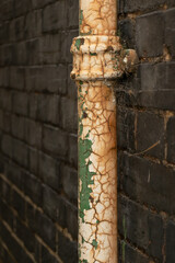 A downpipe in a black brick wall
