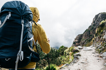 Portrait of solo hiker wearing professional backpack walk across foggy mountains way. Man tourist...