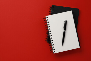 Notebooks and pen on red background, top view. Space for text