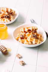 Belgian waffles with honey and nuts on a light background

