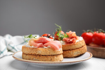 Tasty rusks with prosciutto, cream cheese and tomatoes served on white table