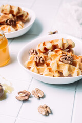 Belgian waffles with honey and nuts on a light background
