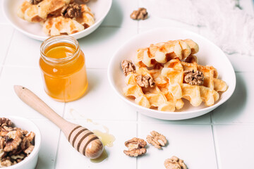 Belgian waffles with honey and nuts on a light background
