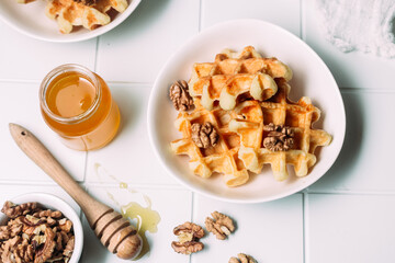 Belgian waffles with honey and nuts on a light background
