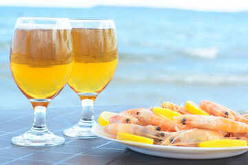 Cold beer in glasses and shrimps served with lemon on beach, closeup