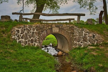 Fototapeta na wymiar Old bridge with wooden railings over a small creek