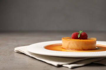 Delicious pudding with caramel and raspberries on grey table. Space for text