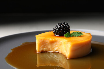 Delicious pudding with caramel and blackberry on plate, closeup