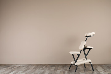 Modern massage chair near beige wall indoors, space for text. Medical equipment