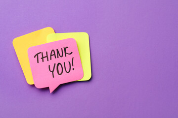Pink paper note with phrase Thank You on purple background, top view. Space for text