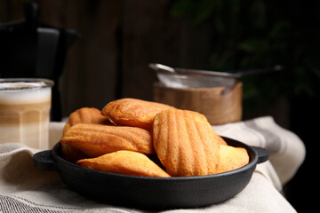 Delicious madeleine cakes in frying pan on table
