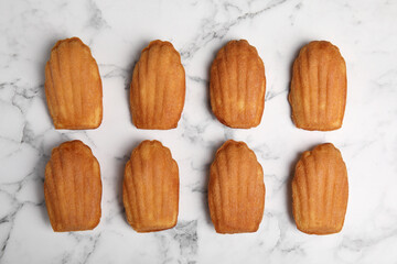 Delicious madeleine cakes on white marble table, flat lay