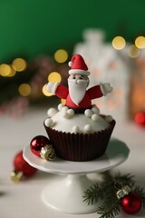 Tasty Christmas cupcake with Santa Claus figure on white table