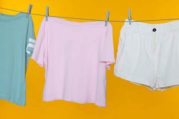 Different clothes drying on laundry line against orange background